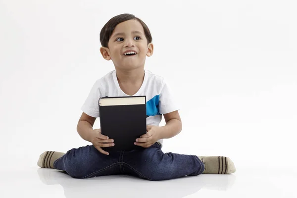 Μαλέι Αγόρι Κάθεται Κρατά Ένα Βιβλίο Που Βλέπει Μακριά — Φωτογραφία Αρχείου
