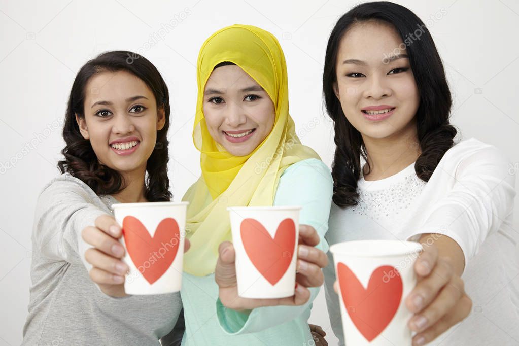 three multi racial malaysian holding cup of love looking at camera