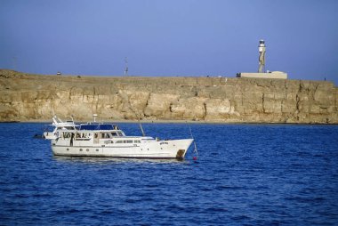 Mısır, Kızıldeniz, Sharm El Sheikh; 6 Mart 2004, dalış tekneleri, kayalık sahil ve deniz feneri yakınındaki şehir - Editörden (Film tarama)