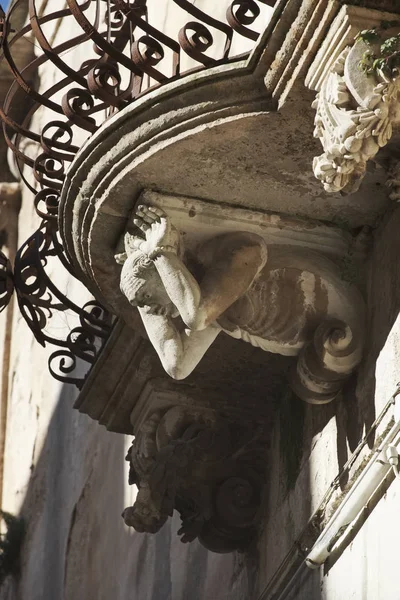 Italy, Sicily, Ragusa Ibla, original statue under a balcony in a baroque palace