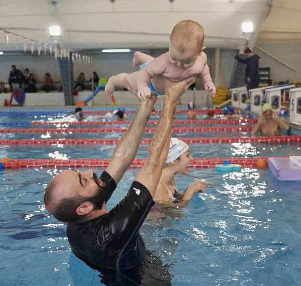 Italien; 19 November 2016, simning tränare undervisning ett nyfött gossebarn i en pool - ledare — Stockfoto