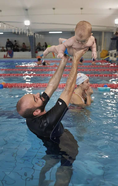 Italien; 19 November 2016, simning tränare undervisning ett nyfött gossebarn i en pool - ledare — Stockfoto