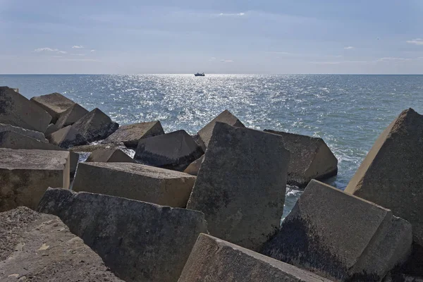 Italia, Mar Mediterraneo, Sicilia, Scoglitti (provincia di Ragusa), blocchi di cemento fuori dal porto e un peschereccio — Foto Stock