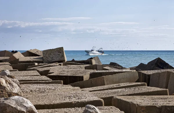 Italie, Méditerranée, Sicile, Scoglitti (province de Raguse), blocs de béton à l'extérieur du port et un bateau de pêche — Photo
