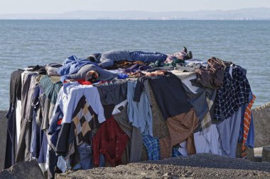 İtalya, Akdeniz, Sicilya, Scoglitti (Ragusa eyaletinde); 8 Mart 2011, Afrika göçmen giysilerini güneşin altında - editoryal kurutma süre bir beton blok Port, Yataklı vagon