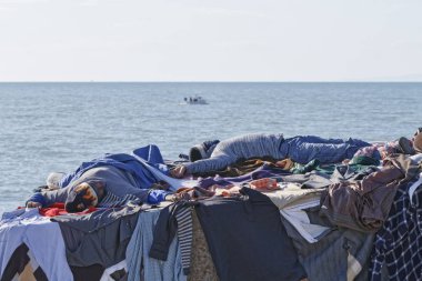 İtalya, Akdeniz, Sicilya, Scoglitti (Ragusa eyaletinde); 8 Mart 2011, Afrika göçmen giysilerini güneşin altında - editoryal kurutma süre bir beton blok Port, Yataklı vagon