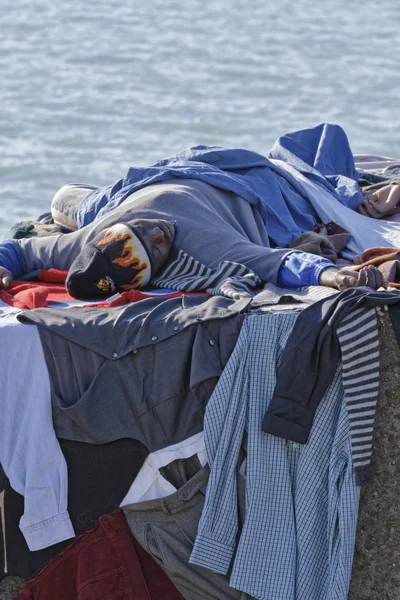 Itália, Mar Mediterrâneo, Sicília, Scoglitti (província de Ragusa); 8 de março de 2011, imigrante africano dormindo em um bloco de concreto no porto, enquanto suas roupas estão secando sob o sol - EDITORIAL — Fotografia de Stock