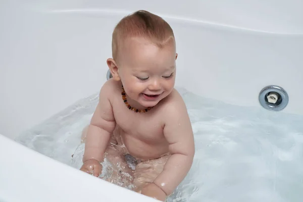 Porträt eines männlichen Säuglings, der mit Wasser in einer Badewanne spielt — Stockfoto