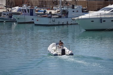 İtalya, Sicilya, Akdeniz; 30 Temmuz 2017, adam bir lastik tekne ve balıkçı tekneleri limanda - Editörden