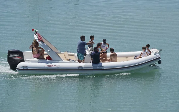Италия, Сицилия, Средиземное море, Marina di Ragusa; 30 июля 2017 года, люди на большой резиновой лодке в порту - РЕДАКЦИЯ — стоковое фото