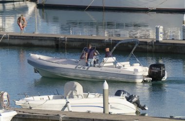 İtalya, Sicilya, Akdeniz, Marina di Ragusa (Ragusa Eyaleti); 2 Kasım 2019, limandaki kauçuk bir teknede insanlar