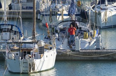 İtalya, Sicilya, Akdeniz, Marina di Ragusa (Ragusa Eyaleti); 20 Kasım 2019, limandaki bir yelkenli teknesindeki insanlar