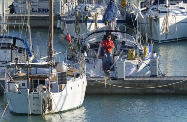İtalya, Sicilya, Akdeniz, Marina di Ragusa (Ragusa Eyaleti); 20 Kasım 2019, limandaki bir yelkenli teknesindeki insanlar