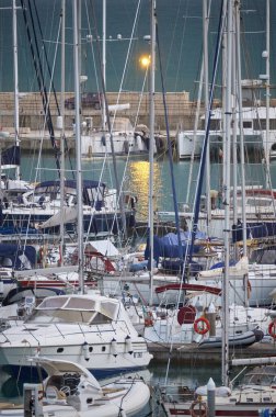 İtalya, Sicilya, Akdeniz, Marina di Ragusa (Ragusa Eyaleti); 5 Aralık 2019, gün batımında limanda motorlu tekne ve lüks yatlar - Yayın