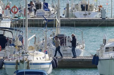 İtalya, Sicilya, Akdeniz, Marina di Ragusa (Ragusa Eyaleti); 5 Ocak 2020, limandaki halk ve yelkenli tekneleri - Editör