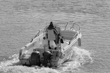 İtalya, Sicilya, Akdeniz, Marina di Ragusa (Ragusa Eyaleti); 11 Ocak 2020, limandaki bir motorlu teknede adam - Editör