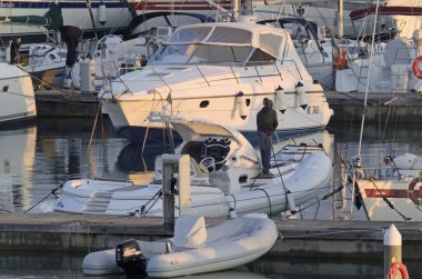 İtalya, Sicilya, Akdeniz, Marina di Ragusa (Ragusa Eyaleti); 15 Ocak 2020, gün batımında limanda bir kauçuk teknede adam - Editör