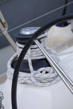Italy, Sicily, Mediterranean Sea, Marina di Ragusa (Ragusa Province); the boat's wheel, a winch and nautical ropes on a sailing boat in the port 