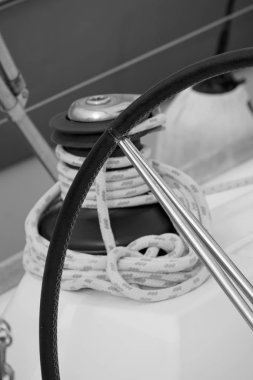 Italy, Sicily, Mediterranean Sea, Marina di Ragusa (Ragusa Province); the boat's wheel, a winch and nautical ropes on a sailing boat in the port 