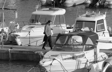 İtalya, Sicilya, Akdeniz, Marina di Ragusa (Ragusa Eyaleti); 6 Mart 2020, limandaki insanlar, motorlu tekneler ve lüks yatlar