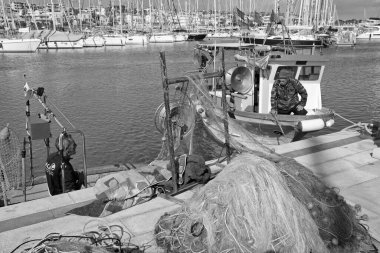 İtalya, Sicilya, Marina di Ragusa (Ragusa Eyaleti), 11 Mart 2020, tahtadan balıkçı tekneleri ve limandaki lüks yatlarda balıkçılar - EDITORIAL