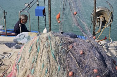 Italy, Sicily, Marina di Ragusa (Ragusa Province); 11 March 2020, nets and a local fisherman on a wooden fishing boat in the port - EDITORIAL