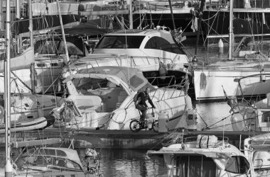 İtalya, Sicilya, Akdeniz, Marina di Ragusa (Ragusa Eyaleti); 3 Nisan 2020, limanda bisiklet ve lüks yatlarda bir adam - EDITORIAL