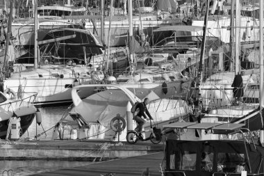 İtalya, Sicilya, Akdeniz, Marina di Ragusa (Ragusa Eyaleti); 3 Nisan 2020, limanda bisiklet ve lüks yatlarda bir adam - EDITORIAL