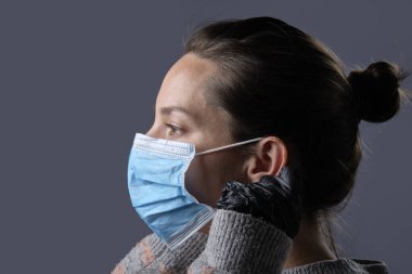 Eldiven ve koruyucu maske takan bir kadının stüdyo portresi.