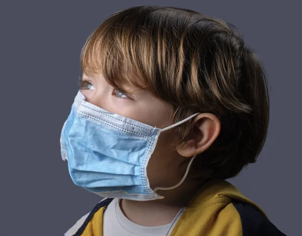 4 yaşında koruyucu maske takan bir erkek çocuğun stüdyo portresi.