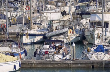 İtalya, Sicilya, Akdeniz, Marina di Ragusa (Ragusa Eyaleti); 12 Nisan 2020, limandaki bir yelkenli teknesinde adam - EDITORIAL