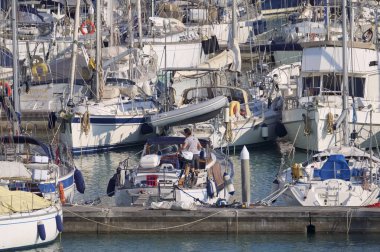 İtalya, Sicilya, Akdeniz, Marina di Ragusa (Ragusa Eyaleti); 12 Nisan 2020, limandaki bir yelkenli teknesinde adam - EDITORIAL