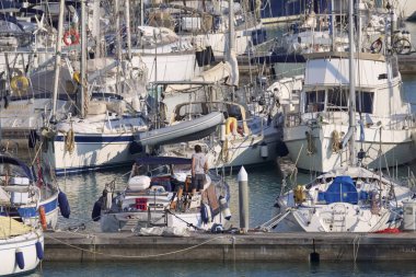 İtalya, Sicilya, Akdeniz, Marina di Ragusa (Ragusa Eyaleti); 12 Nisan 2020, limandaki bir yelkenli teknesinde adam - EDITORIAL