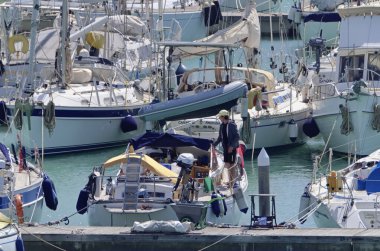İtalya, Sicilya, Akdeniz, Marina di Ragusa (Ragusa Eyaleti); 15 Nisan 2020, limandaki bir yelkenli teknesinde adam - EDITORIAL