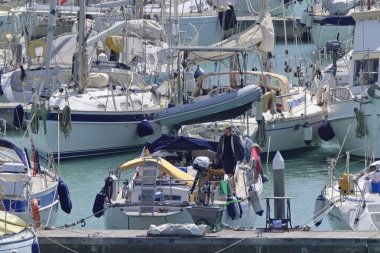 İtalya, Sicilya, Akdeniz, Marina di Ragusa (Ragusa Eyaleti); 15 Nisan 2020, limandaki bir yelkenli teknesinde adam - EDITORIAL