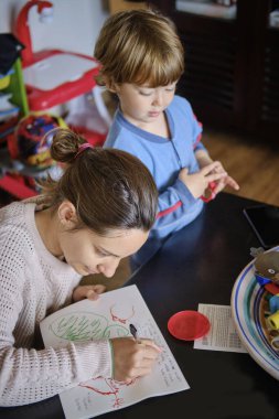 Anne, 4 yaşındaki erkek çocuğuna ev ödevinde yardım ediyor.