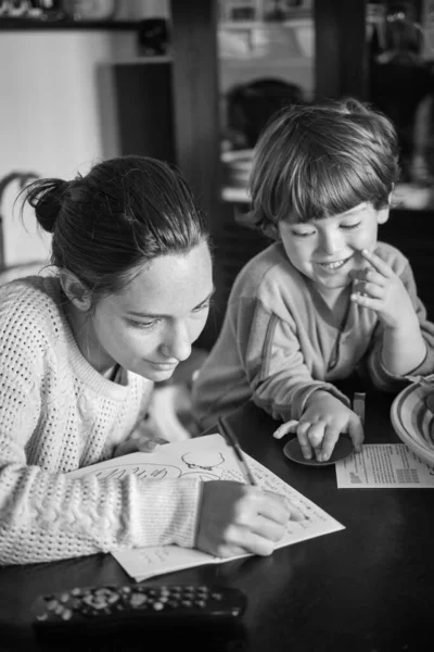 Mother helping her 4 yeras old male child with his homework at home