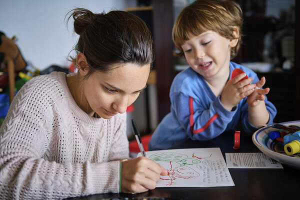 Mother helping her 4 yeras old male child with his homework at home