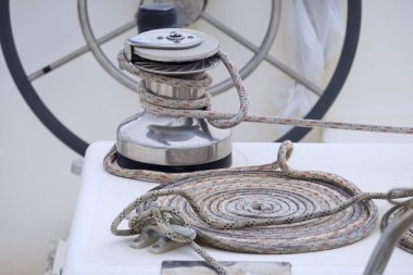 Italy, Sicily, Mediterranean Sea, Marina di Ragusa (Ragusa Province); the boat's wheel, a winch and nautical ropes on a sailing boat in the port 