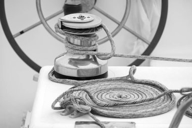 Italy, Sicily, Mediterranean Sea, Marina di Ragusa (Ragusa Province); the boat's wheel, a winch and nautical ropes on a sailing boat in the port 