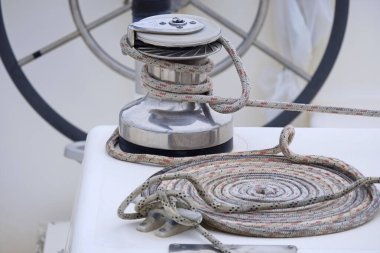 Italy, Sicily, Mediterranean Sea, Marina di Ragusa (Ragusa Province); the boat's wheel, a winch and nautical ropes on a sailing boat in the port 