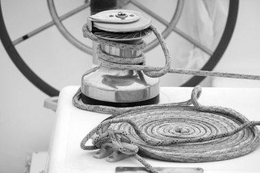 Italy, Sicily, Mediterranean Sea, Marina di Ragusa (Ragusa Province); the boat's wheel, a winch and nautical ropes on a sailing boat in the port 