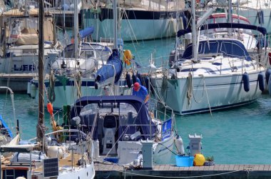 İtalya, Sicilya, Akdeniz, Marina di Ragusa (Ragusa Eyaleti); 1 Mayıs 2020, limandaki bir yelkenli teknesinde adam - EDITORIAL