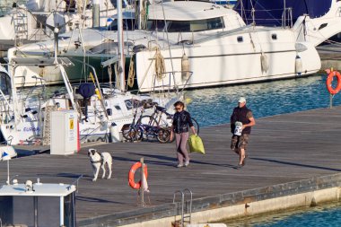 İtalya, Sicilya, Akdeniz, Marina di Ragusa (Ragusa Eyaleti); 3 Mayıs 2020, limanda köpek ve lüks yatları olan insanlar - EDITORIAL