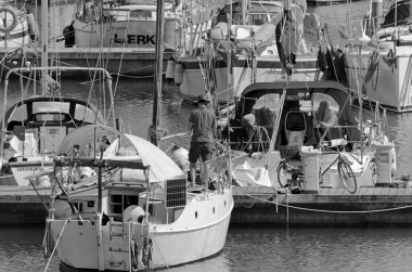 İtalya, Sicilya, Akdeniz, Marina di Ragusa (Ragusa Eyaleti); 6 Mayıs 2020, limandaki bir yelkenli teknesinde adam - EDITORIAL