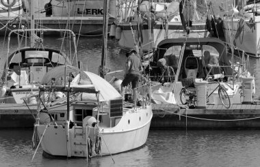 İtalya, Sicilya, Akdeniz, Marina di Ragusa (Ragusa Eyaleti); 6 Mayıs 2020, limandaki bir yelkenli teknesinde adam - EDITORIAL