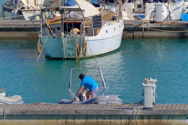 İtalya, Sicilya, Akdeniz, Marina di Ragusa (Ragusa Eyaleti); 22 Mayıs 2020, limandaki kauçuk bir teknede adam - EDITORIAL