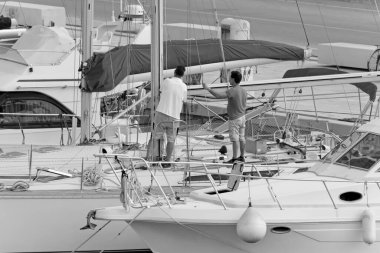 İtalya, Sicilya, Akdeniz, Marina di Ragusa (Ragusa Eyaleti); 26 Mayıs 2020, limandaki bir yelkenli teknesinde insanlar - EDITORIAL