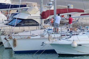 İtalya, Sicilya, Akdeniz, Marina di Ragusa (Ragusa Eyaleti); 26 Mayıs 2020, limandaki bir yelkenli teknesinde insanlar - EDITORIAL