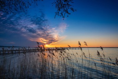 Sakin bir gölün üzerinde güzel, renkli bir gün batımı.